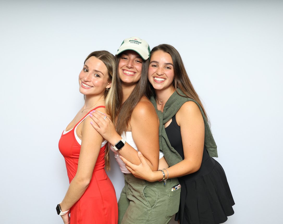 Three friends hugging and laughing in front of a white backdrop