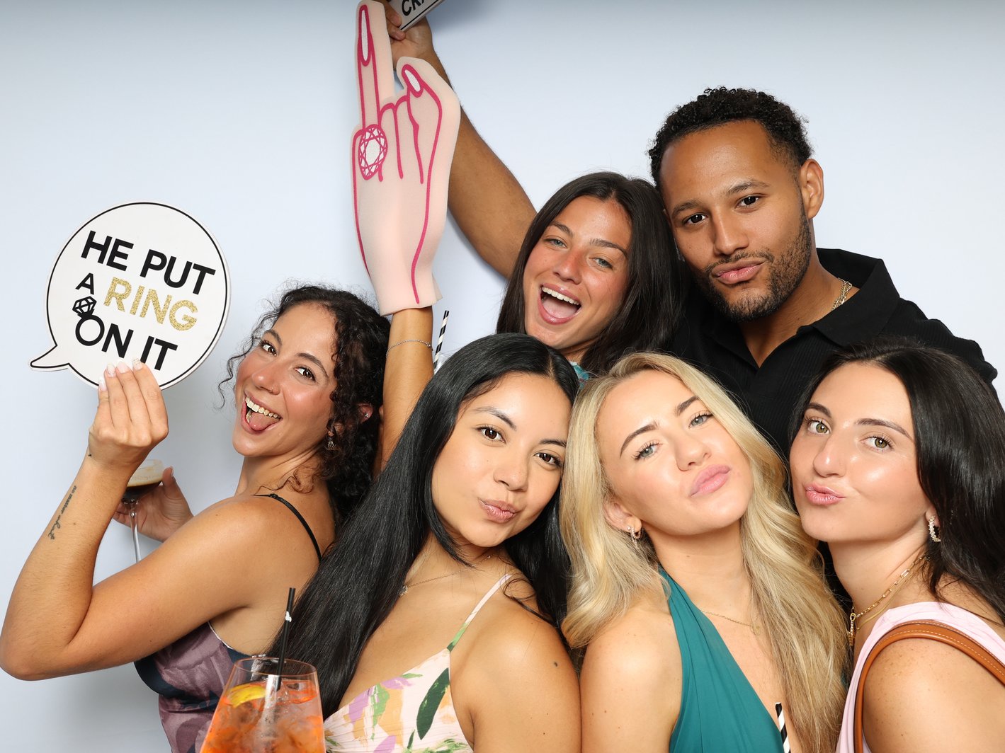 Friends posing with a pointing hand prop and a hand-held sign