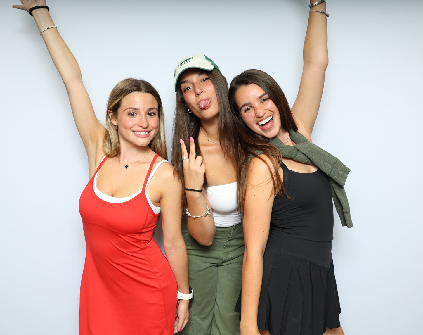 Three friends with their arms raised in front of a white backdrop