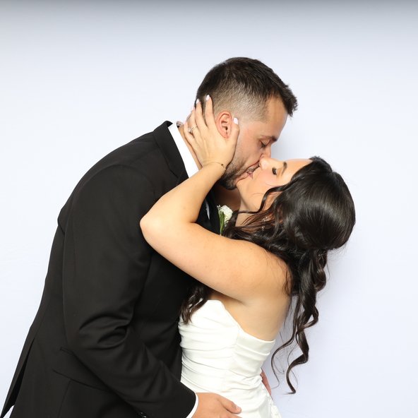 A couple kissing in front of a white backdrop