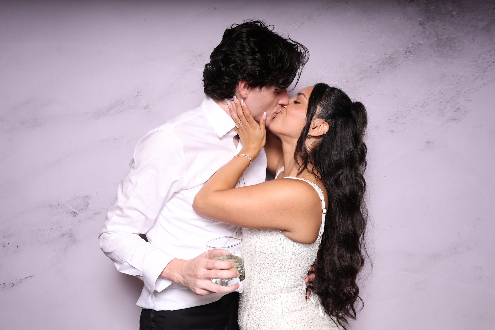 A couple kissing in front of a marble backdrop